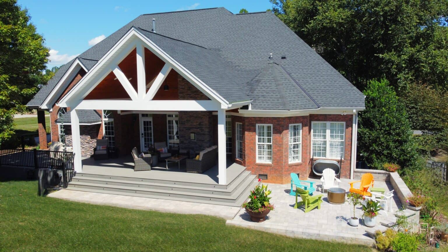 Aerial view of a brick home with a white gabled covered porch and adjoining stone patio