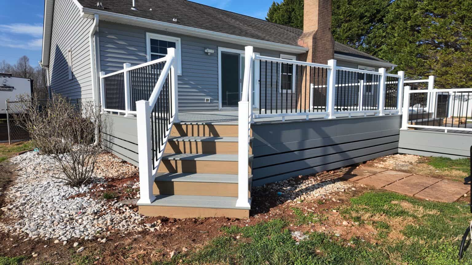 New composite deck with white railings and black balusters on a gray home